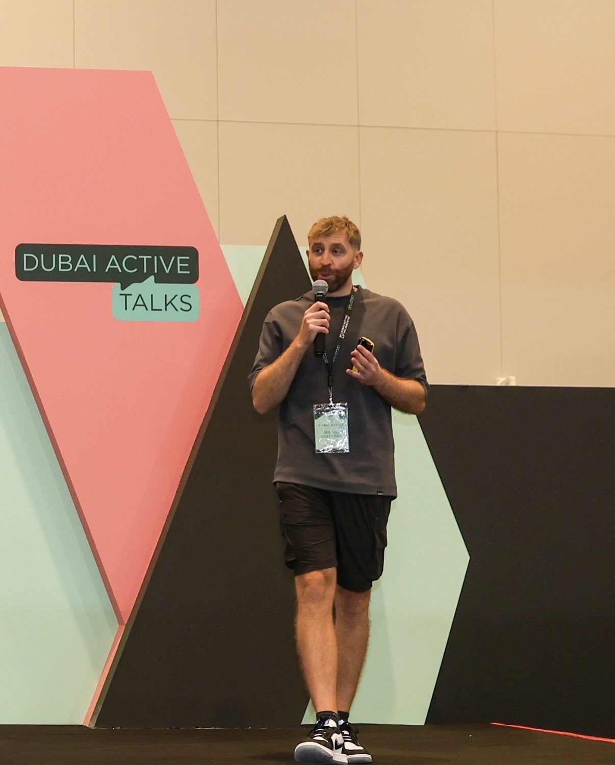 Graeme Tomlinson on stage at Dubai Active Talks holding a microphone.